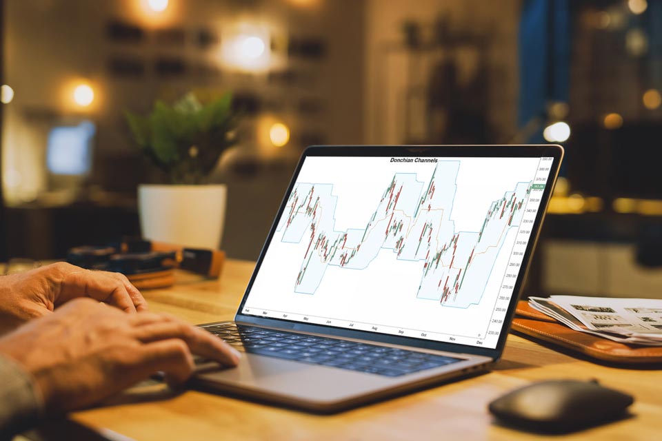 A person analyzing a laptop screen displaying a Donchian Channel trading chart, illustrating the Donchian Channel Indicator