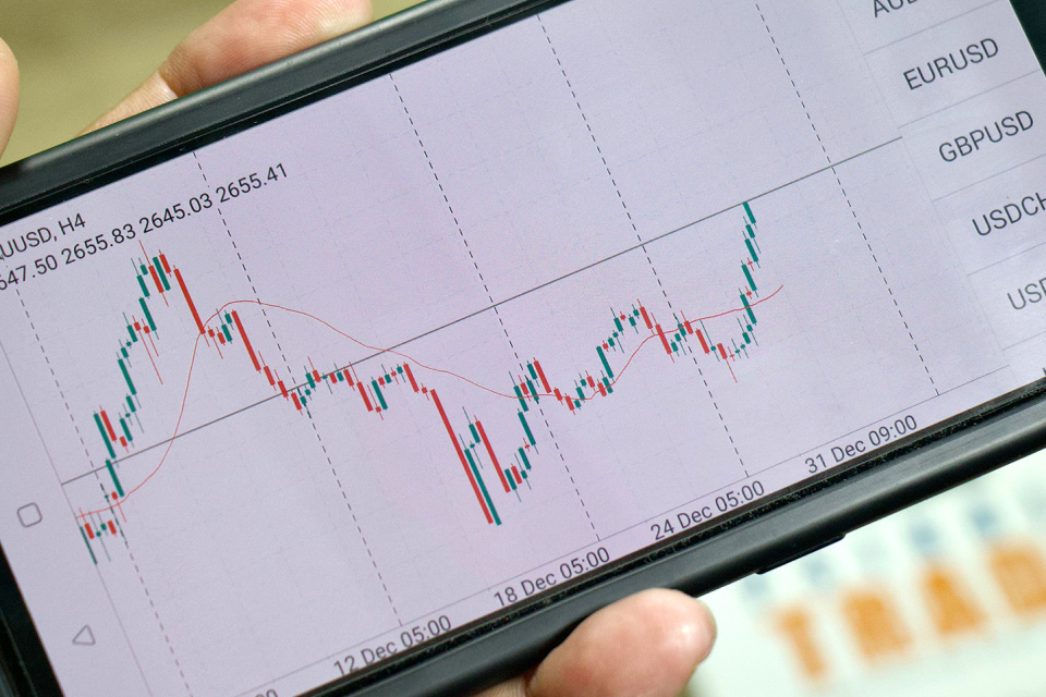 Mastering Chart Types in MetaTrader 5 – A trader analyzing candlestick patterns and price movements on a smartphone trading app.