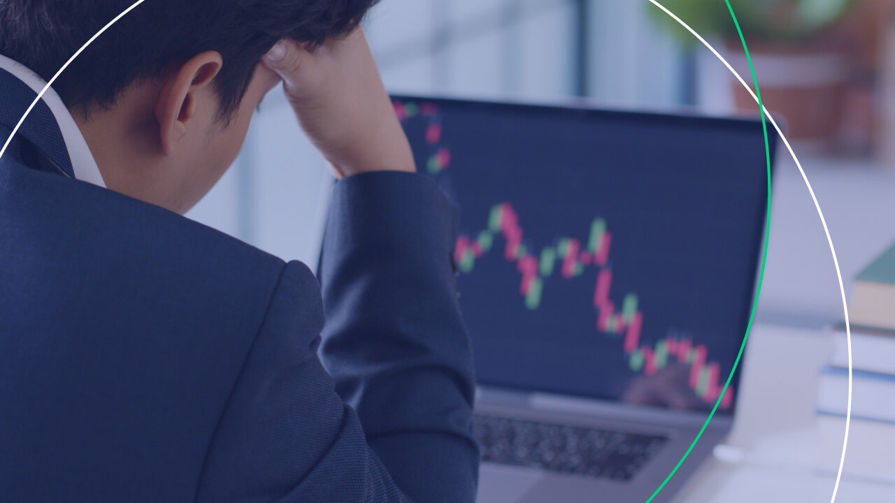 A stressed businessman in a suit looks at a laptop screen showing a declining candlestick chart, indicating a possible trading loss, illustrating why traders lose money in intraday trading.
