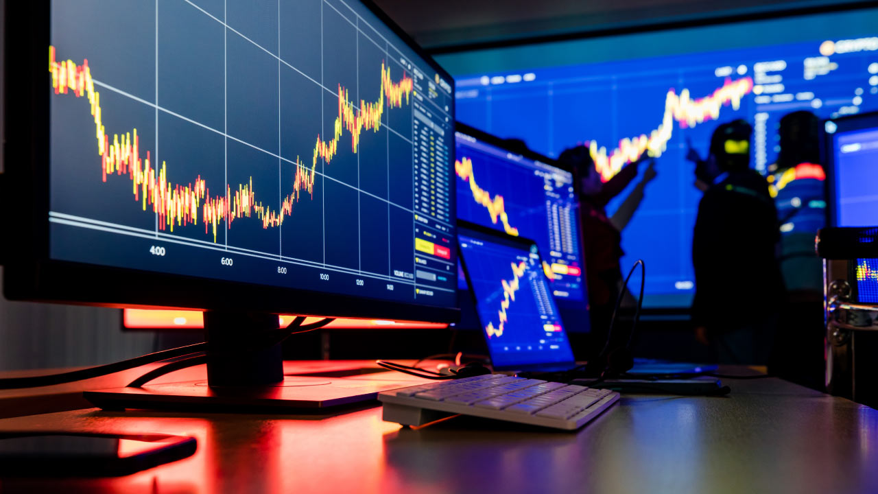 5 Exit Strategies to Consider in Forex Trading. A high-tech trading setup displaying forex market charts, with traders analyzing price movements on multiple screens, representing strategic exit planning in forex trading.