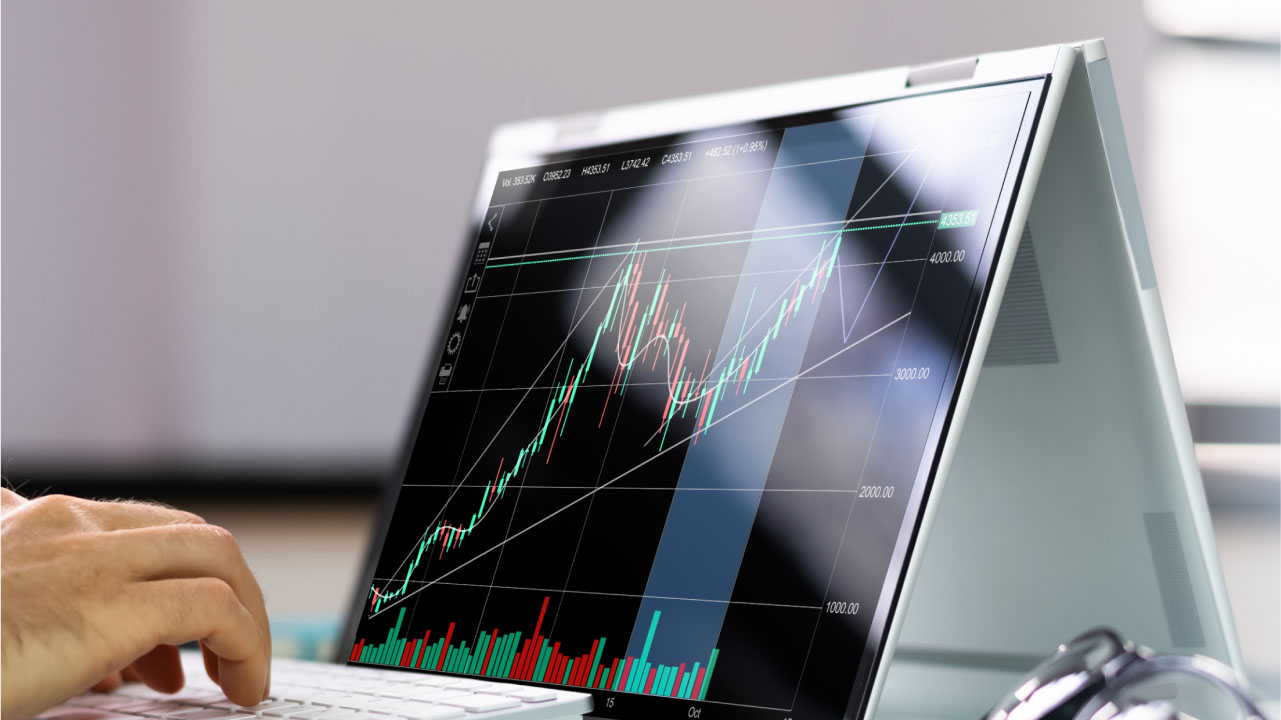 A person using a laptop displaying the MetaTrader 4 (MT4) trading platform
