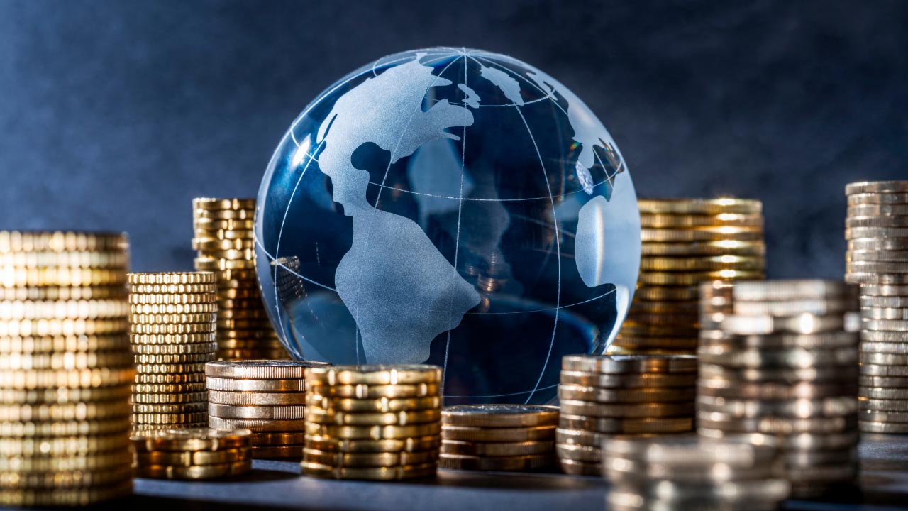 How Central Banks Impact the Forex Market – A glass globe surrounded by stacks of gold coins, symbolizing the influence of central banks on global currencies and forex trading.