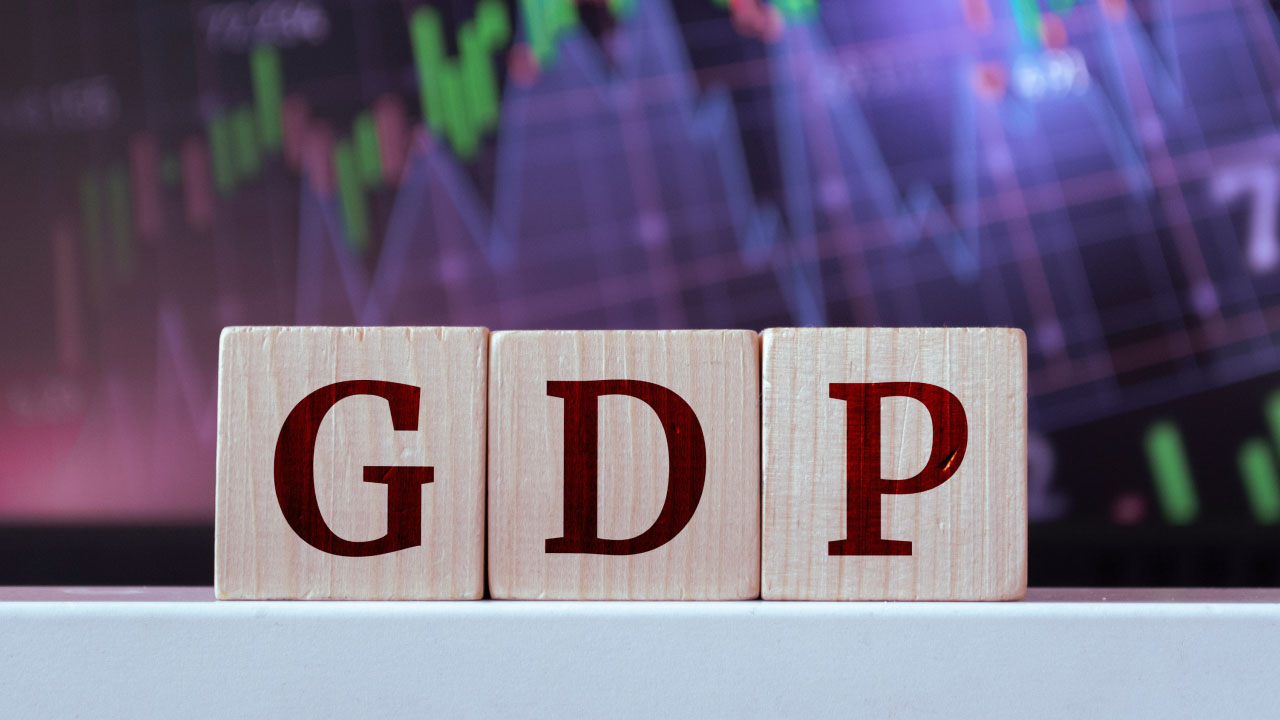 How Does GDP Affect the Stock Market? Wooden blocks spelling 'GDP' in front of a stock market chart, illustrating what GDP is and how it impacts stock prices and investor sentiment.