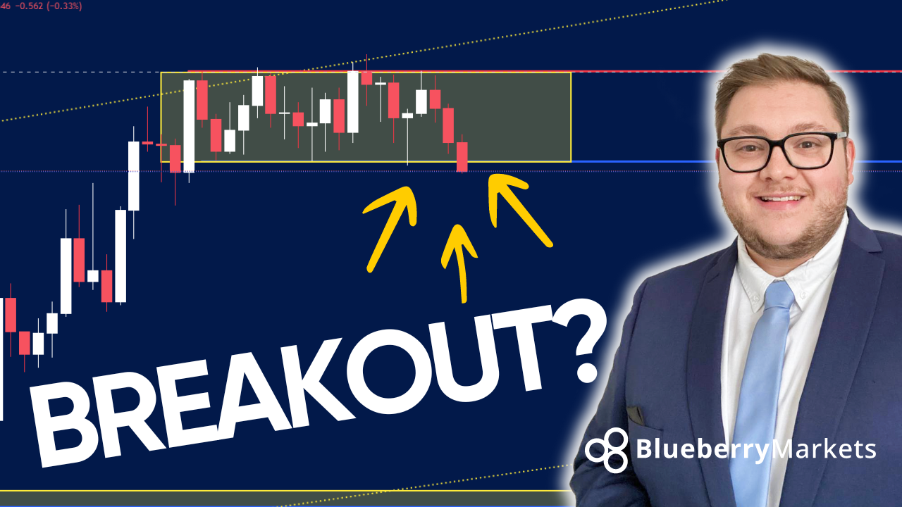 A man in a suit and tie stands beside a candlestick chart showing a breakout below a consolidation zone, highlighted by a yellow box and yellow arrows pointing down.