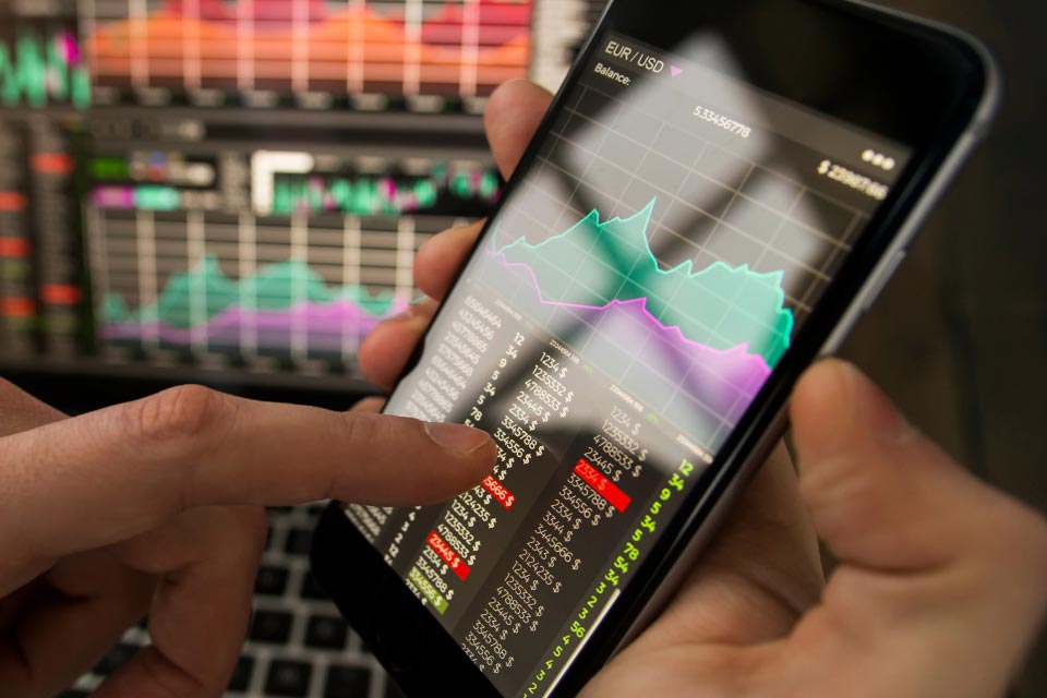 A trader analyzing forex market data on a smartphone with charts and currency pairs, illustrating what forex is