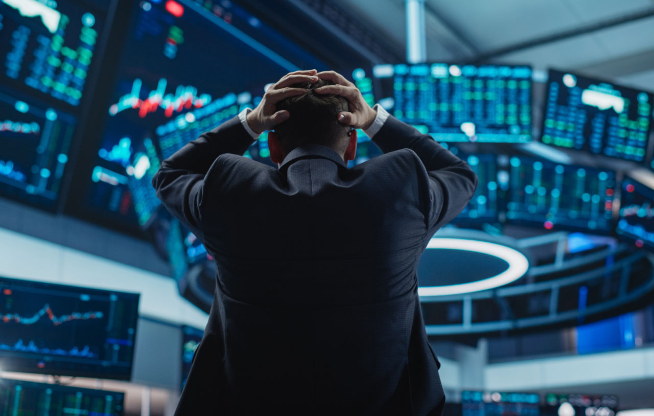 Top Ways to Minimize Missed Trades, illustrated by an image of a person holding his head in shock inside a trading office with screens and charts.