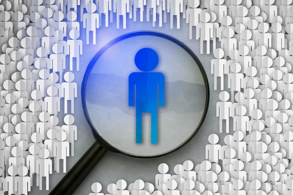 a magnifying glass focusing on a single blue figure among a crowd of white figures