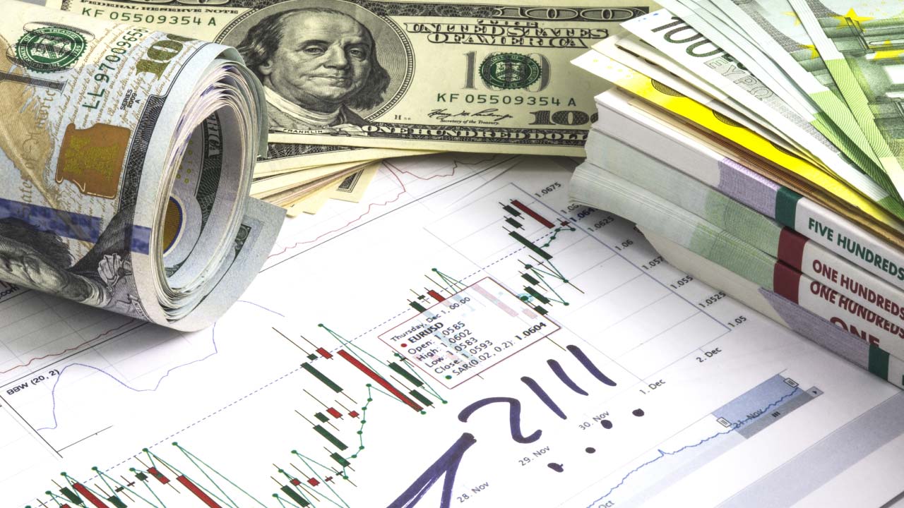 Rolled and stacked US dollar and euro banknotes placed on a forex trading chart displaying candlestick patterns and annotations. What is a Lot in Forex?