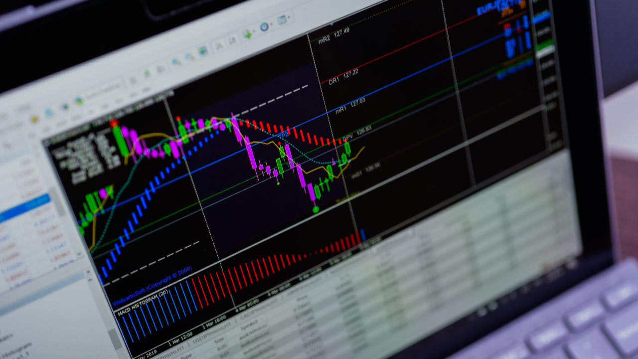 a trading platform displayed on a laptop screen, featuring colorful candlestick charts and technical indicators
