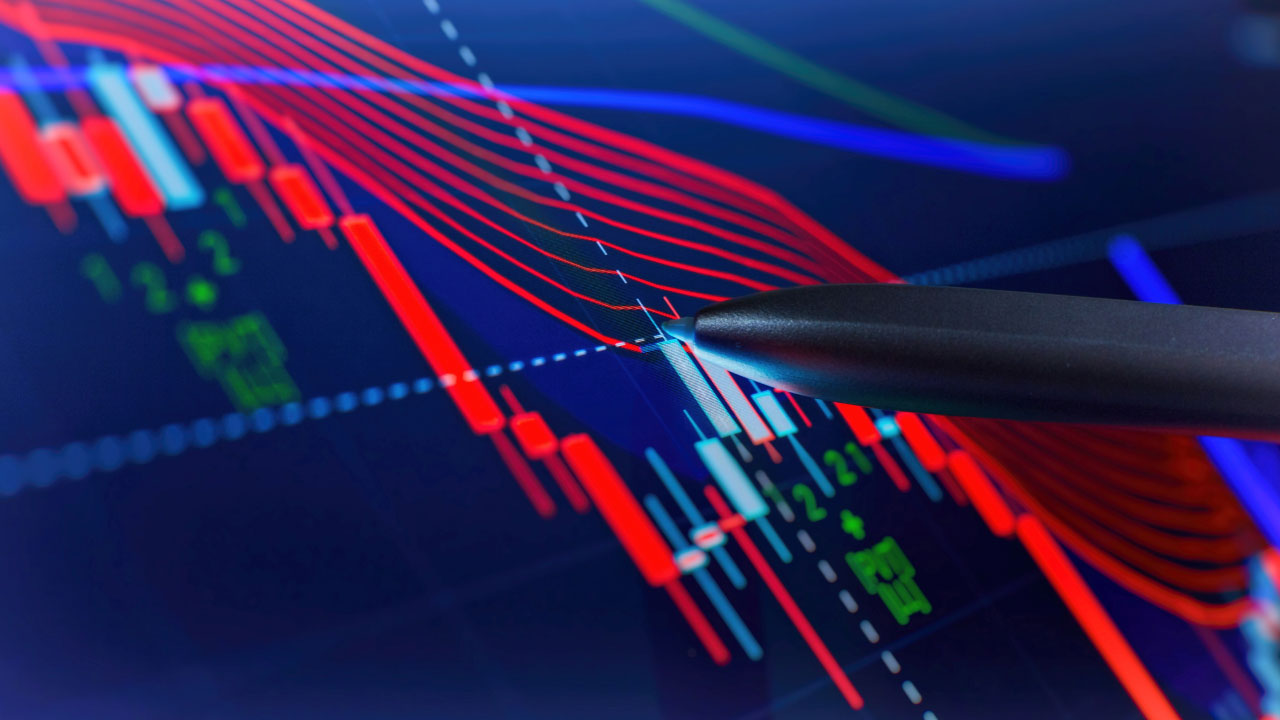 Pen pointing at a digital trading chart displaying red and blue candlesticks and multiple technical indicators on a dark background, illustrating the concept of Position Trading.