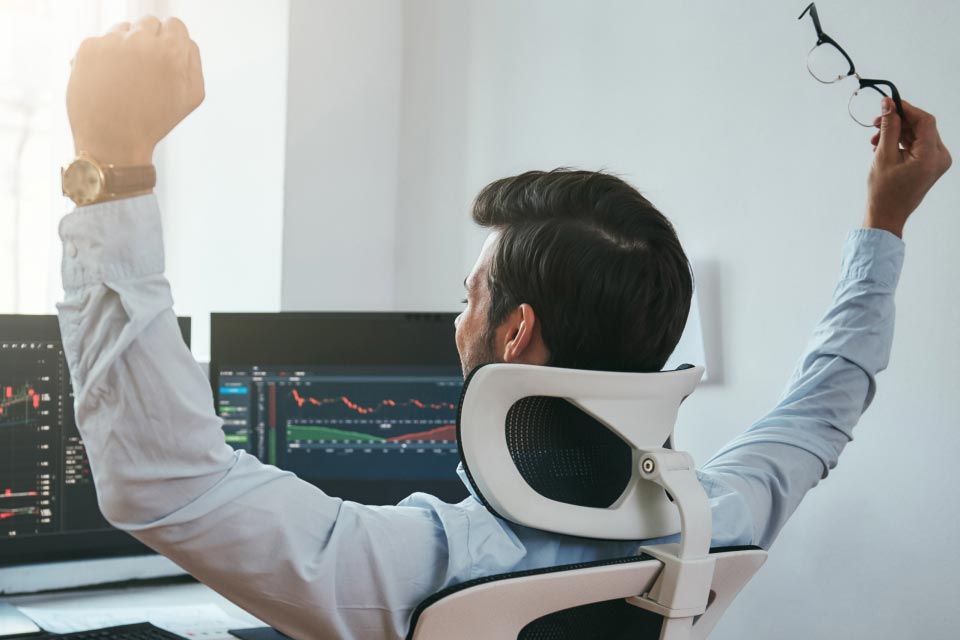 Habits of Successful Forex Traders illustrated by a back view of a trader celebrating success, raising arms in victory.