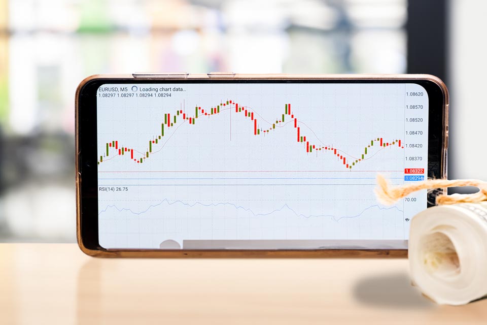 A smartphone displaying an MT4 trading chart with indicators, showing EUR/USD price movement and RSI values, illustrating how traders can add and use indicators for analysis.