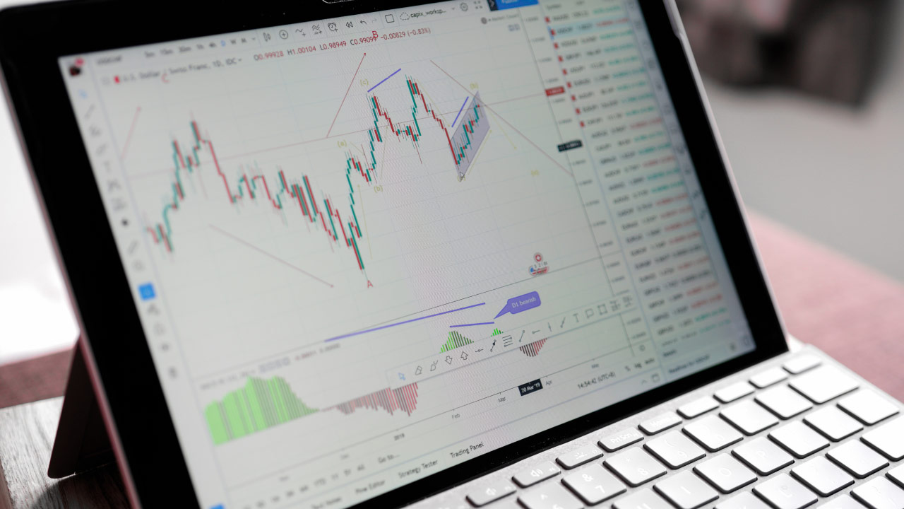Scalping vs. Position Trading: Which is Right for You?, illustrated by a close-up of a laptop screen displaying a technical trading chart on a financial platform.