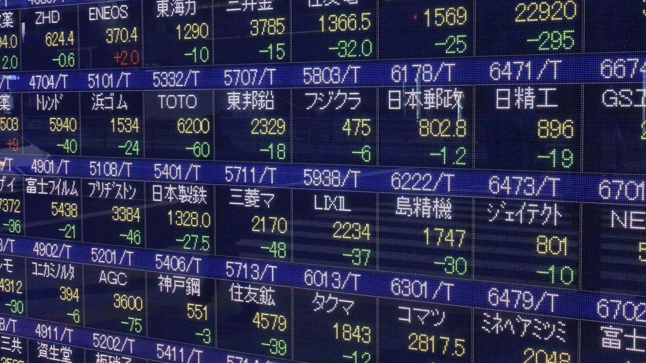 Managing Risk When Investing in the Tokyo Stock Exchange from Vietnam — illustrated by an electronic display board showing Japanese stock market listings with company names, ticker symbols, and numerical data including stock prices and daily changes.