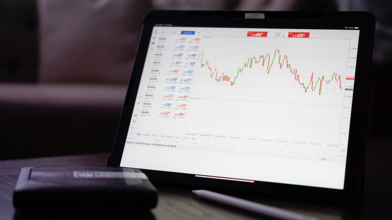 A tablet displaying a trading platform with a candlestick chart and forex price quotes, illustrating how to install expert advisors on MT5 for automated trading strategies.