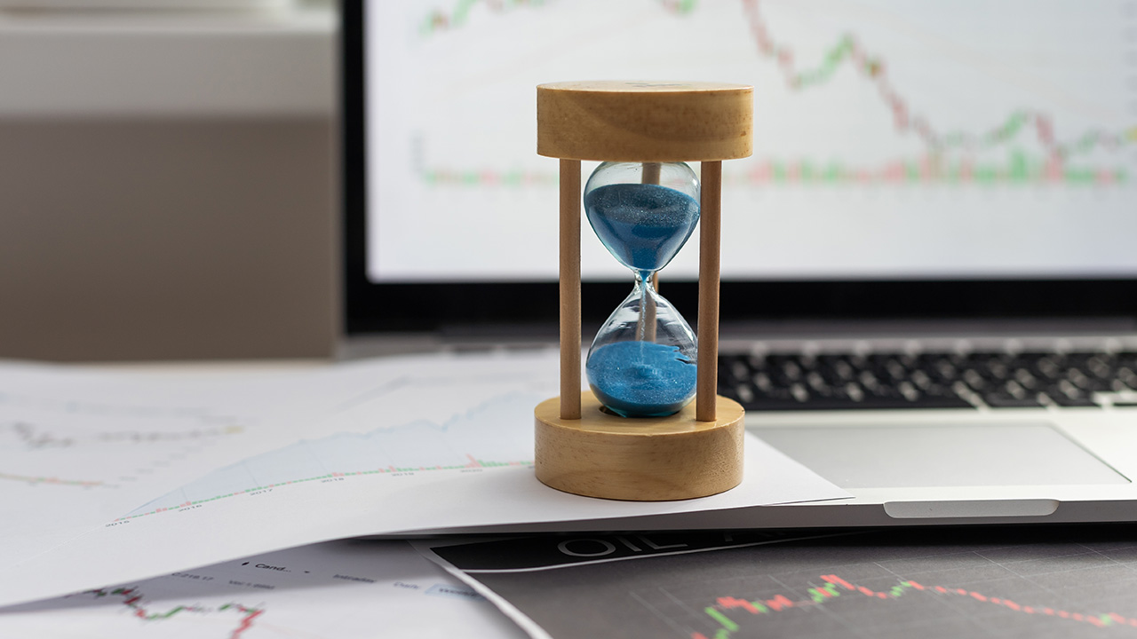 A picture showing an hourglass on top of a laptop, illustrating forex cycles analysis and timing market movements