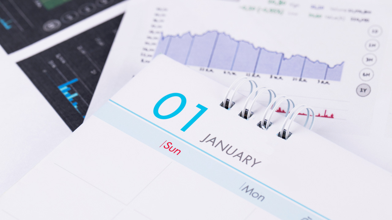 A close-up of a calendar displaying January 1st alongside financial charts, representing how traders can read and utilize the forex economic calendar for market analysis.
