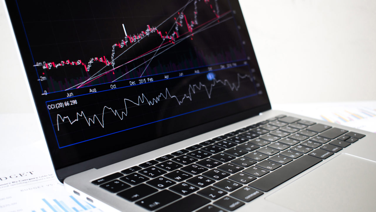 a laptop screen displaying a trading chart with various indicators and timeframes, illustrating how to change timeframes on MT5.
