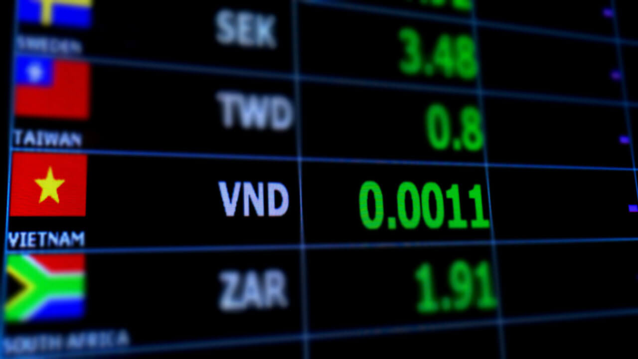 Exchanging Foreign Currency to Vietnamese dong: Pros And Cons – A digital foreign exchange rate display featuring the Vietnamese dong (VND) with a value of 0.0011, alongside country flags and other currency rates.