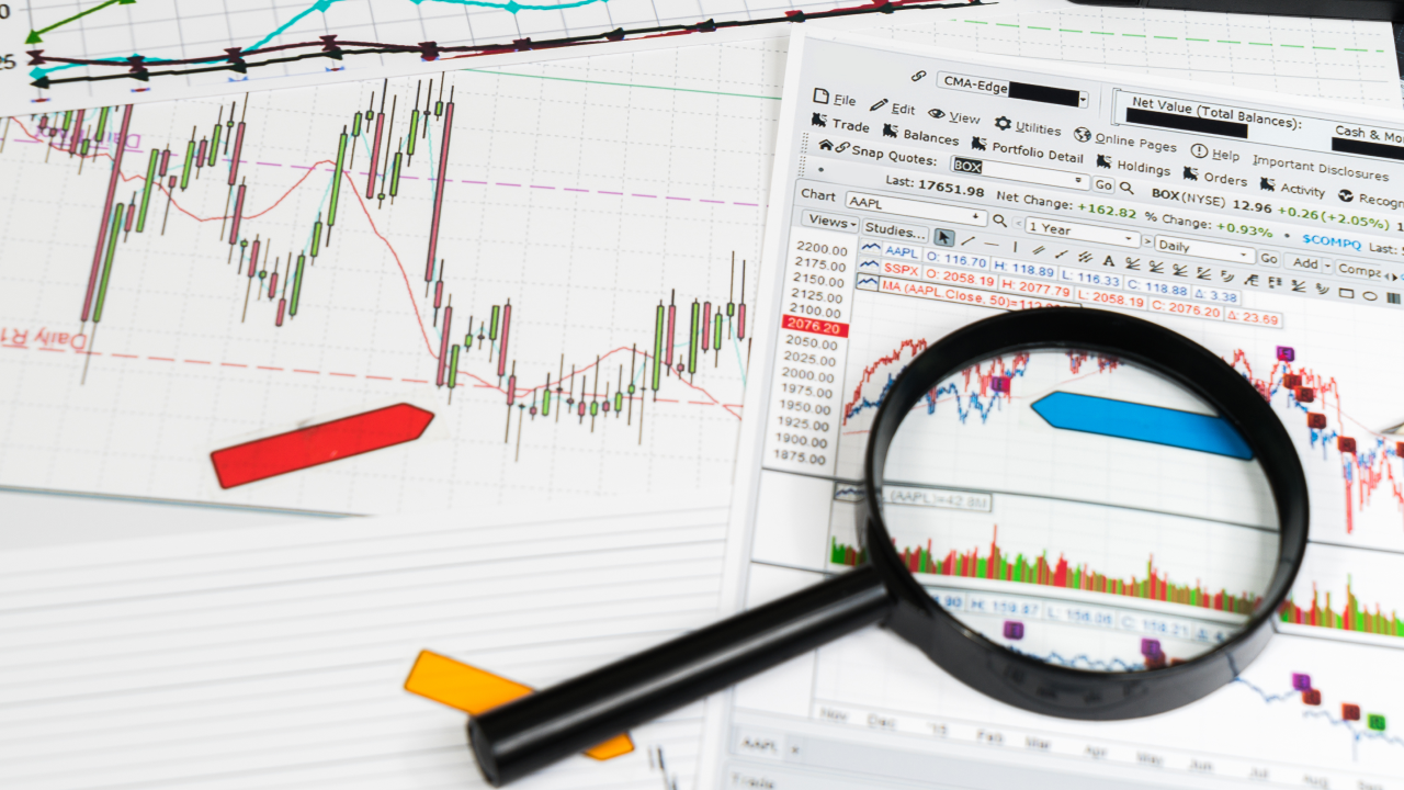 A magnifying glass placed over trading charts, symbolizing the concept of stop-loss hunting and strategies to avoid market manipulation.
