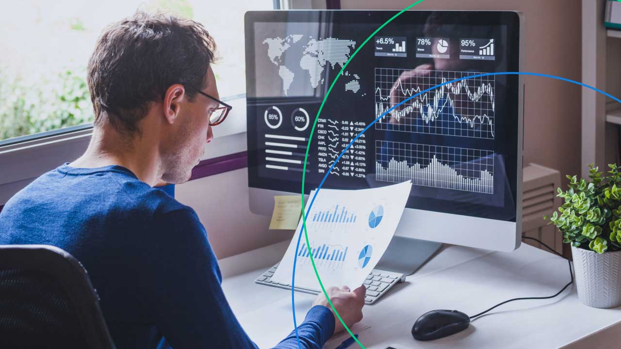 A trader analyzing charts and financial data on a computer screen, holding a printed report with graphs, representing 16 effective day trading strategies for beginners.