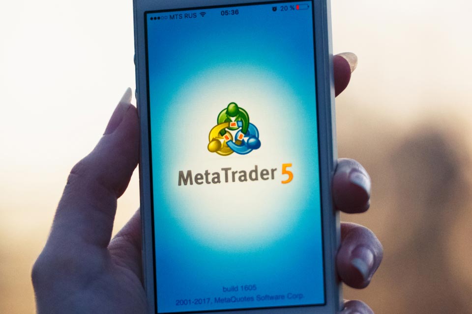 Hand holding a smartphone displaying the MetaTrader 5 logo on the screen, highlighting the powerful trading platform for forex, stocks, CFDs, and futures.