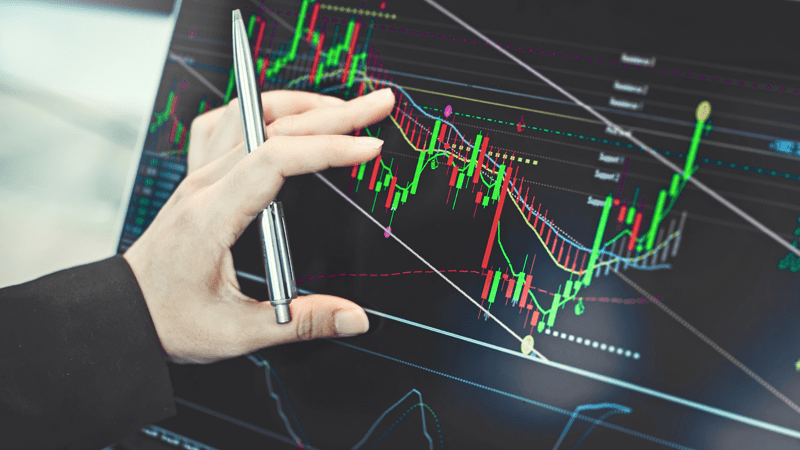 Close-up of a hand using a pen to interact with a computer screen, illustrating the concept of Algorithmic Trading.