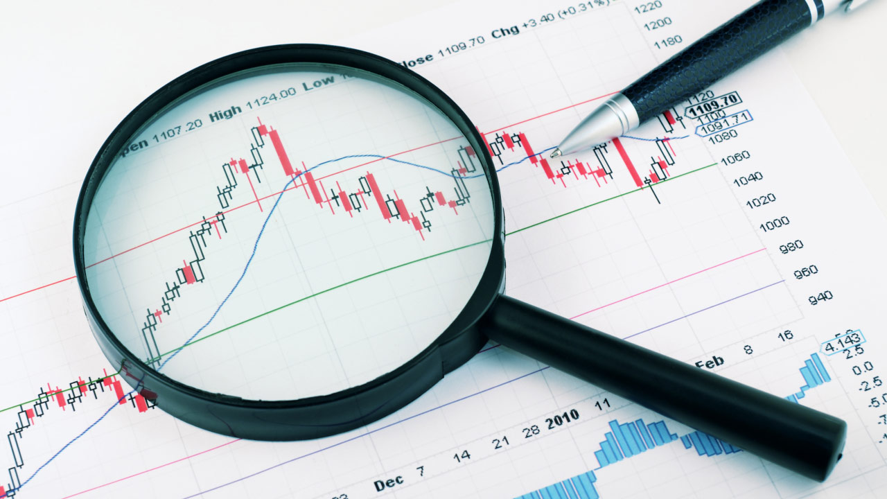 What is the ICT trading strategy? A magnifying glass focusing on a financial chart with candlestick patterns, trend lines, and technical indicators, symbolizing in-depth market analysis using Inner Circle Trader (ICT) concepts.