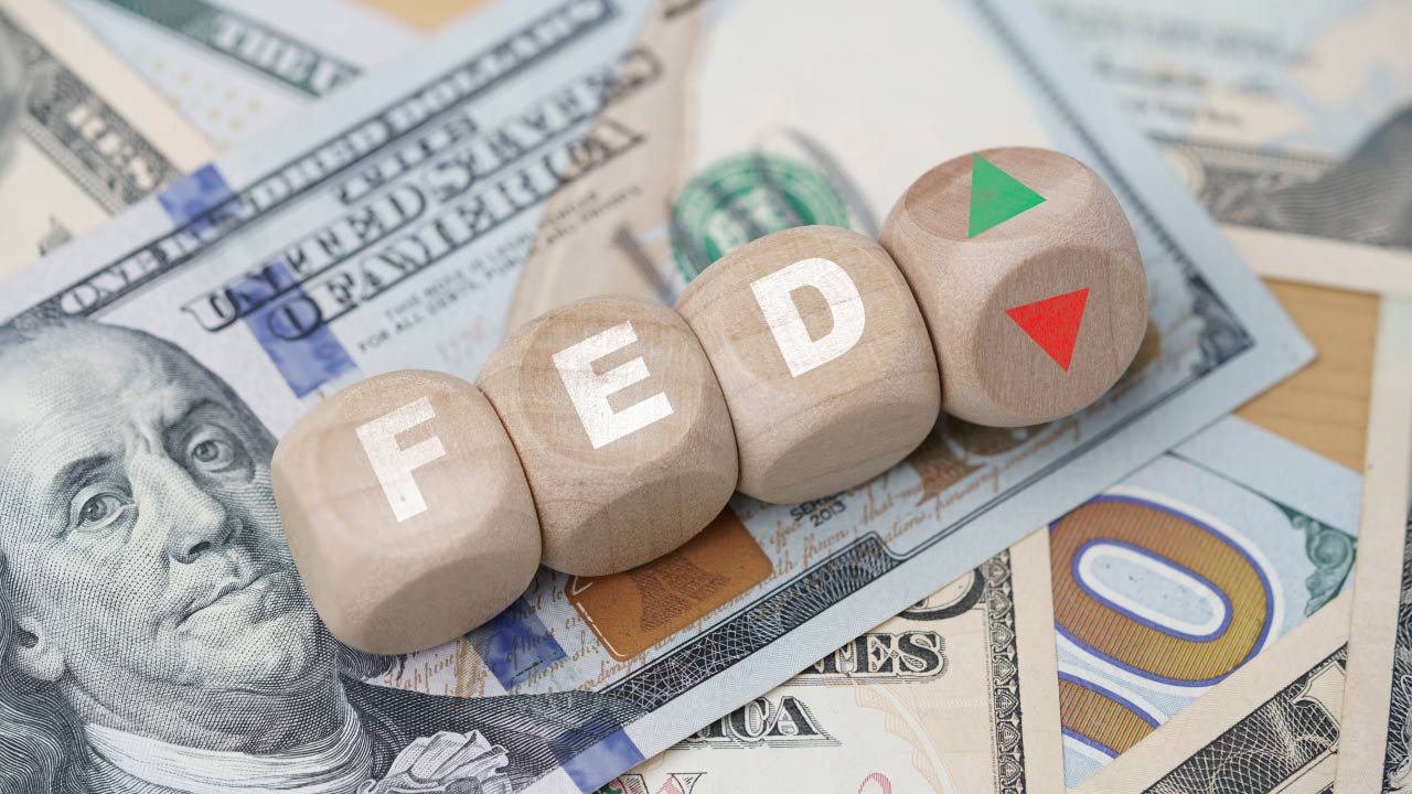 wooden blocks spelling "FED" placed on 100 US dollar bills
