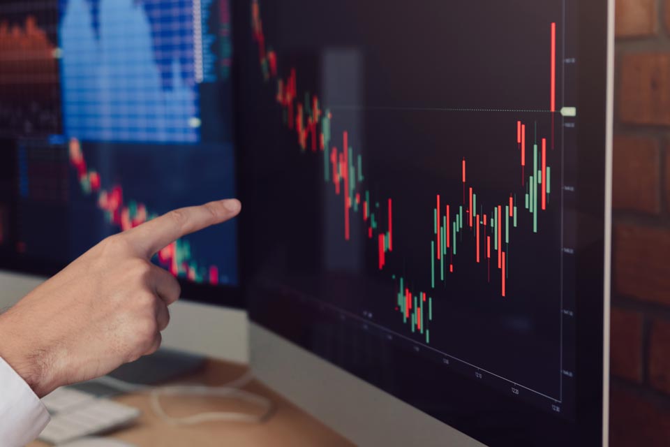 Person pointing to a screen displaying forex charts and market data, illustrating how to use forex market sentiment indicators.