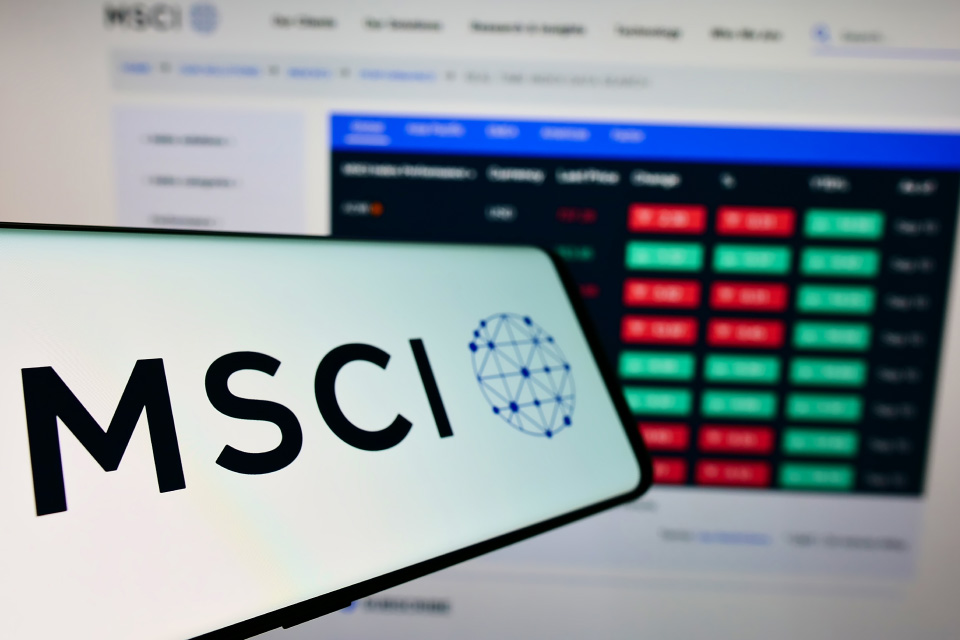 a smartphone showing the MSCI logo with a blurred background of a computer screen