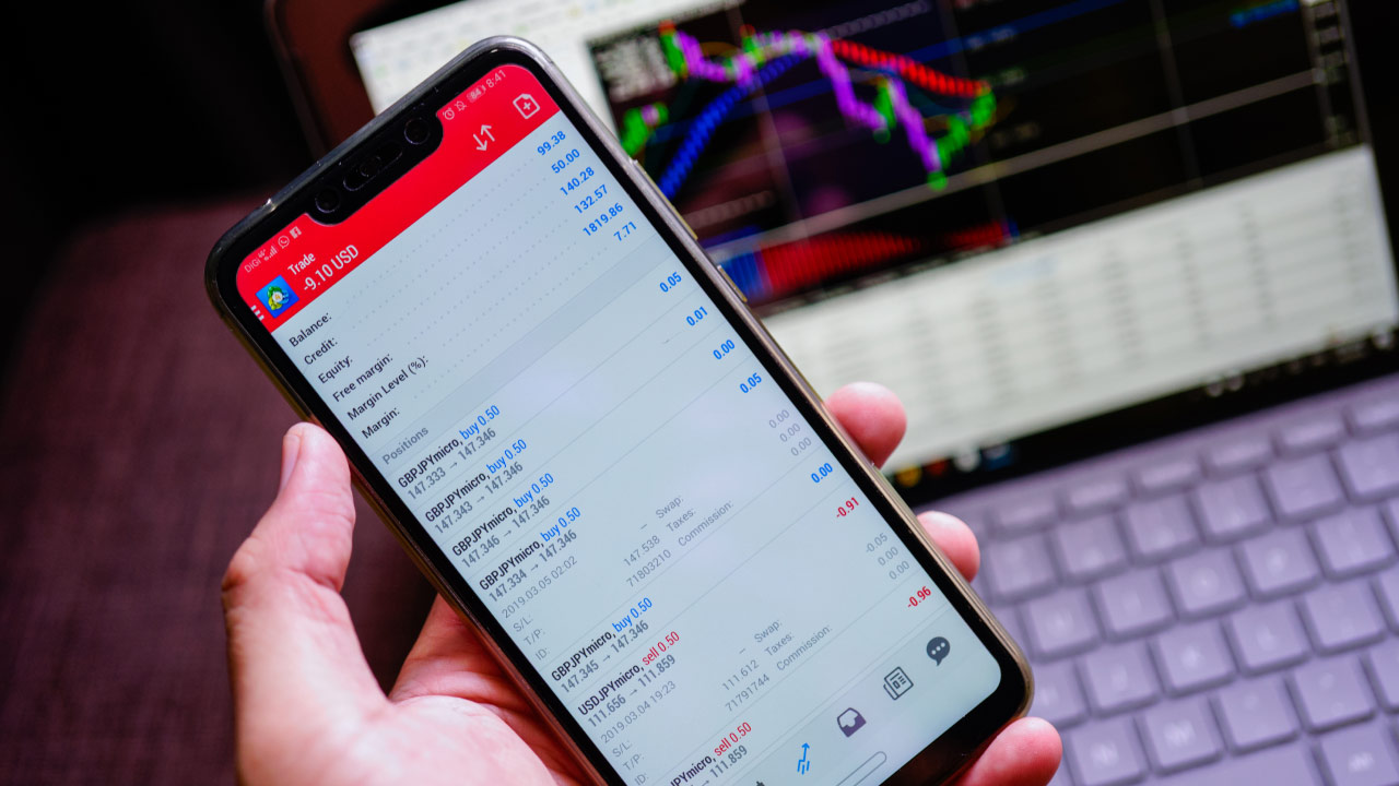 Optimizing MT4 and MT5 Performance with VPS: Configuration Tips and Tricks, illustrated by a person holding a smartphone displaying a trading app with a live account balance.
