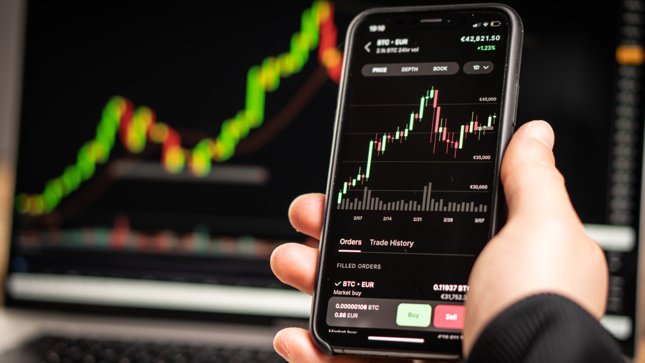 Person holding a smartphone displaying a Bitcoin to Euro (BTC/EUR) candlestick price chart with a rising trend, illustrating the concept of what price charts are and how to use them.