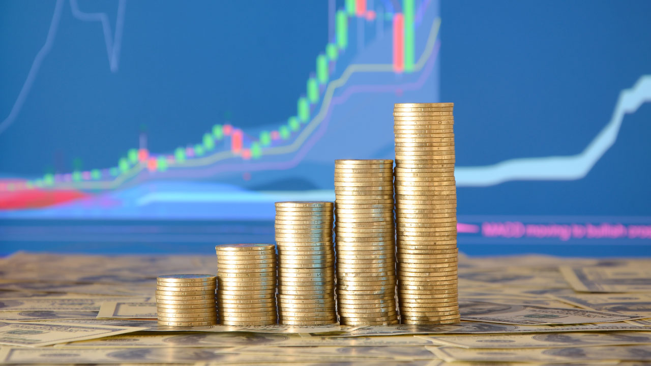 Stacks of gold coins arranged in ascending order on top of dollar bills, illustrating the concept of Leverage in Forex.