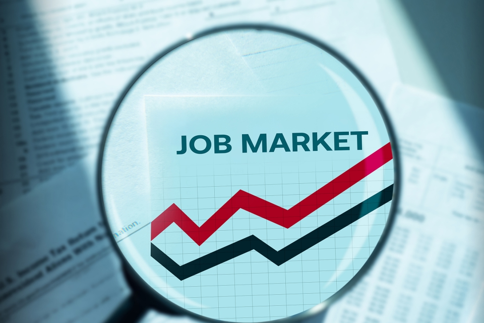 Magnifying glass highlighting the phrase 'JOB MARKET' over a background of rising red and black trend lines on a graph, illustrating Forex Week Ahead Analysis: 13th January.