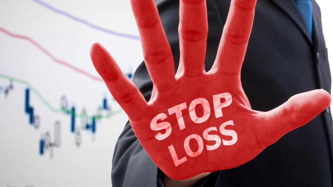 A trader in a suit raising a red hand with 'STOP LOSS' written on it, symbolizing risk management in day trading, with a financial chart in the background.
