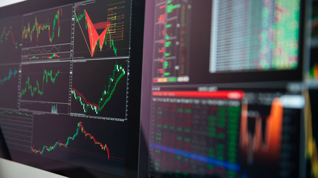 Difference between trading on demo accounts and live accounts – A multi-screen trading setup displaying market charts, price trends, and technical indicators, illustrating the contrast between simulated and real trading environments.