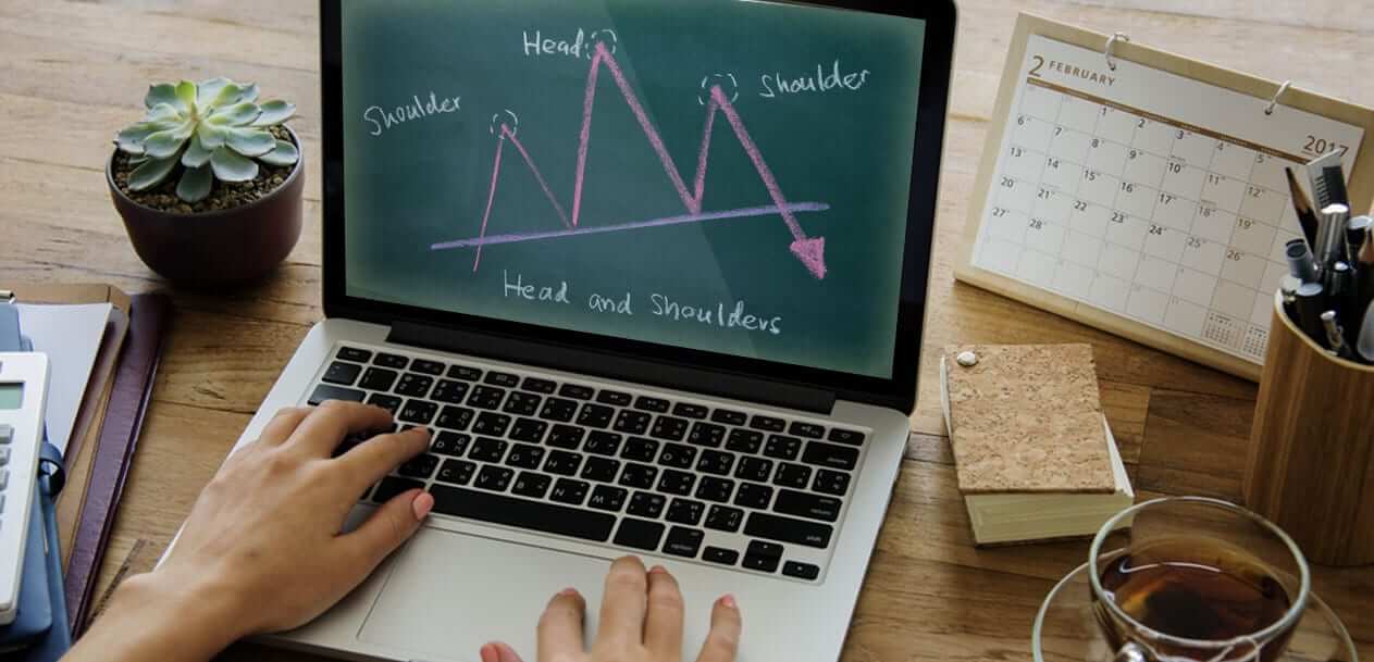 Trading with the Head and Shoulders Pattern displayed on a laptop screen, illustrating a technical analysis chart with labeled peaks and trendlines.