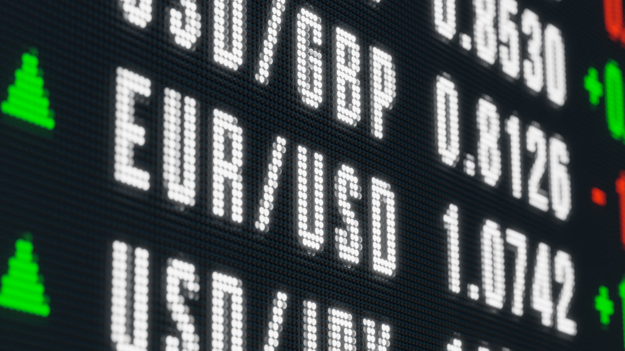 A digital forex display board showing currency pairs and exchange rates including USD/GBP, EUR/USD, and USD/JPY with green and red arrows indicating price movement directions.