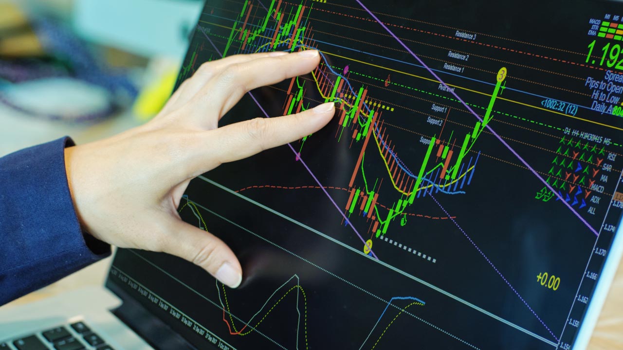 A trader analyzing a financial chart on a touchscreen laptop, displaying trend indicators, resistance and support levels, and technical analysis tools, relevant to the Aroon Indicator.