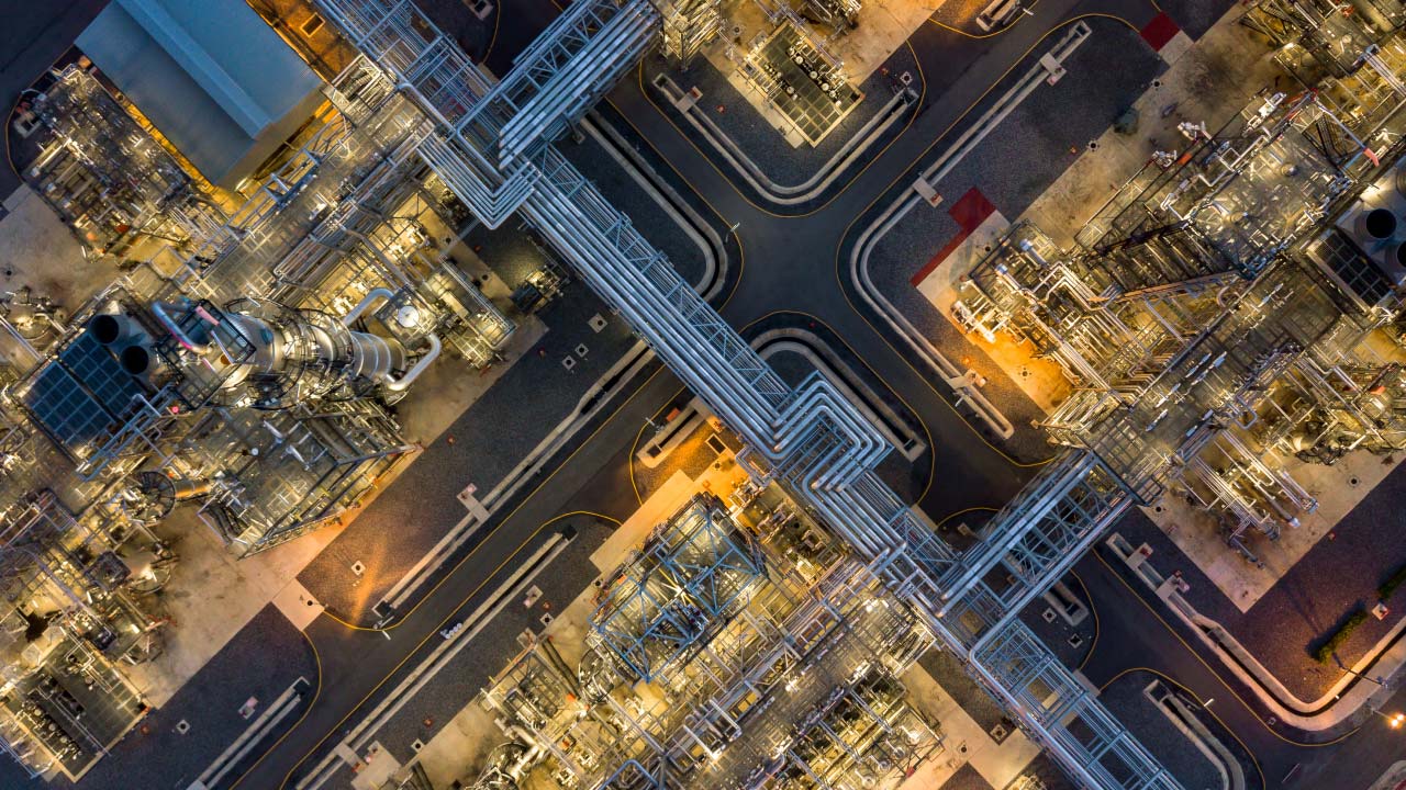 Top Industries to Invest in on the Tokyo Stock Exchange for Vietnamese Investors, illustrated by an aerial view of a large industrial complex with pipelines and illuminated structures, representing industrial investment opportunities.