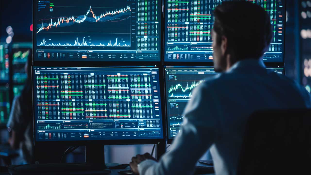 Can You Use MetaTrader 4 Without A Broker? – A trader analyzing multiple monitors displaying real-time forex and stock market data, representing the functionality of MetaTrader 4 and its potential use without a broker.