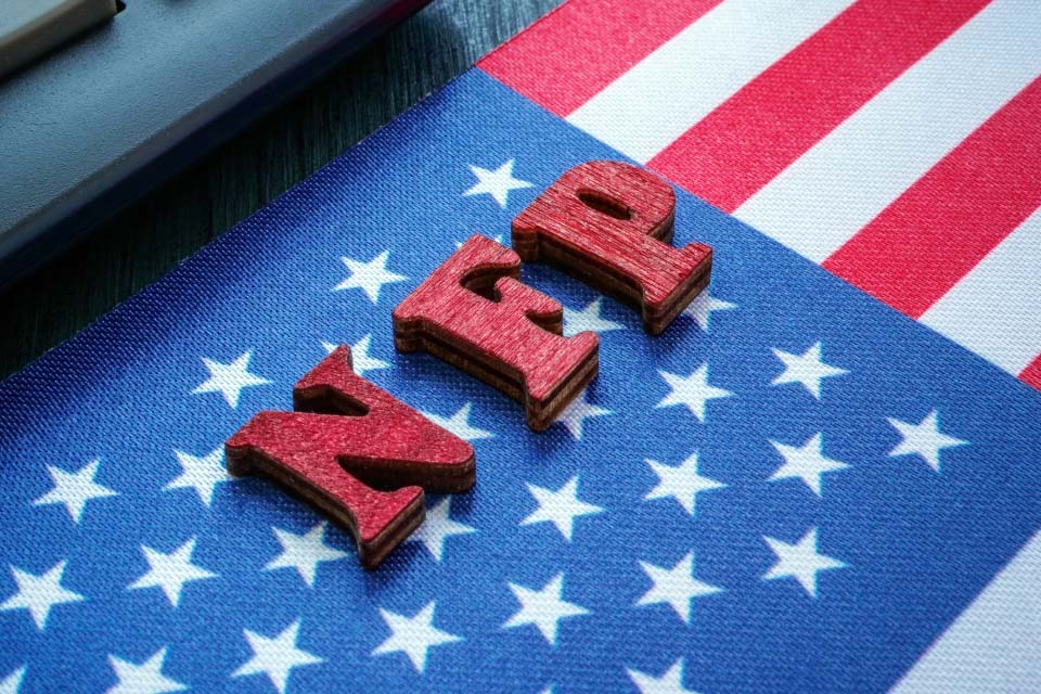 Wooden letters spelling 'NFP' placed on an American flag, symbolizing the U.S. Non-Farm Payroll report, a key event in the Forex Week Ahead Analysis: 3rd March.