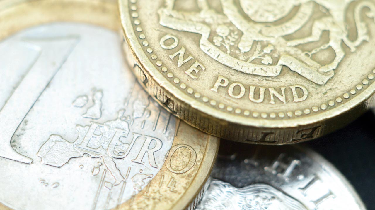currency coins featuring a British one pound coin overlapping a one euro coin