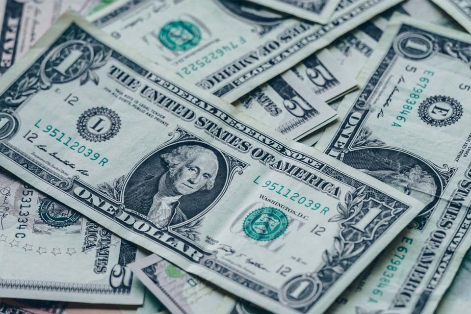 A collage of US dollar notes illustrating dollar fluctuation as investors weigh rate cut chances